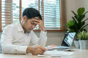 Stressed and headache asian man with large bills or invoices no money to pay to expenses and credit card debt. shortage, Financial problems, mortgage, loan, bankruptcy, bankrupt, poor, empty wallet photo