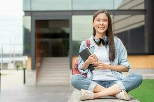 Beautiful student asian woman with backpack and books outdoor. Smile girl happy carrying a lot of book in college campus. Portrait female on international Asia University. Education, study, schoo photo