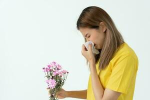 polen alergias, asiático joven mujer estornudos en un pañuelo o soplo en un limpiar, alérgico a salvaje primavera flores o flores durante primavera. alérgico reacción, respiratorio sistema problemas foto