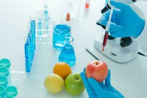 Scientist check chemical food residues in laboratory. Control experts inspect quality of fruit, scientists inject chemicals into apples for experiments, hazards, prohibited substance, contaminate photo