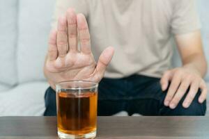 man refuses say no and avoid to drink an alcohol whiskey , stopping hand sign male, alcoholism treatment, alcohol addiction, quit booze, Stop Drinking Alcohol. Refuse Glass liquor, unhealthy, reject photo