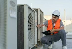 Asian maintenance engineer works on the roof of factory. contractor inspect compressor system and plans installation of air condition systems in construction. Checklist, inspector, control photo