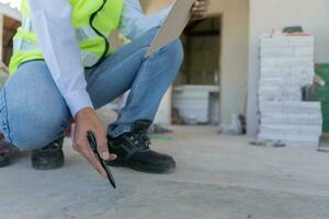 el inspector o ingeniero está inspeccionando la construcción y el aseguramiento de la calidad de la nueva casa usando una lista de verificación. ingenieros o arquitectos o contratistas trabajan para construir la casa antes de entregársela al propietario foto