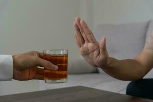 man refuses say no and avoid to drink an alcohol whiskey , stopping hand sign male, alcoholism treatment, alcohol addiction, quit booze, Stop Drinking Alcohol. Refuse Glass liquor, unhealthy, reject photo