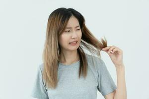 Asian woman very sad and upset looking at damaged hair, hair loss, hair thinning problem, vitamin deficiency, baldness, postpartum, biotin, zinc, menstrual or endocrine disorders, hormonal imbalance photo