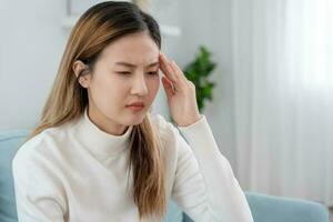 Headache, female having migraine pain, bad health, Asian woman feeling stress and headache, Office syndrome, sad tired touching forehead having migraine or depression, irritated girl, sadness grief photo