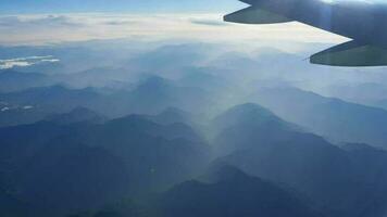 hermosa ver mediante avión ventana, avión volador encima brumoso río en montañas. China territorio. video