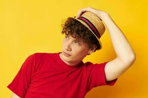 Young curly-haired man emotions red t-shirt hat studio yellow background unaltered photo