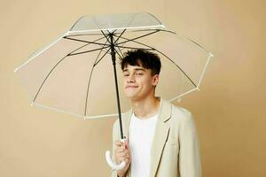 a man with an open umbrella in a jacket protection from the rain beige background photo