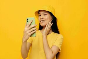 retrato asiático hermosa joven mujer en un amarillo sombrero y camiseta hablando en el teléfono estilo de vida inalterado foto