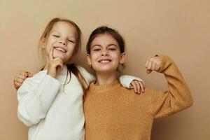 dos gracioso pequeño muchachas en suéteres posando infancia foto