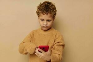 boy in a sweater with a phone in his hands technology beige background photo