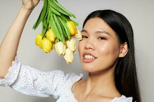 Portrait Asian beautiful young woman with a bouquet of flowers smile close-up light background unaltered photo