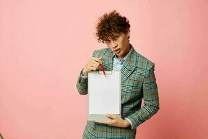 portrait of a young curly man in a business suit copy-space documents pink background unaltered photo