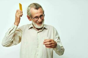 Elderly man combing his hair with a yellow comb in the studio on a gray background photo