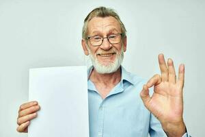 Photo of retired old man holding a sheet of paper copy-space posing isolated background