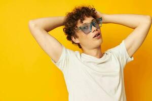 portrait of a young curly man in a white t-shirt blue fashion glasses isolated background unaltered photo