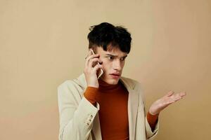 foto joven novio móvil teléfono en el manos de comunicación en un traje Moda ligero antecedentes inalterado