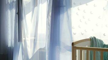 leeg baby jongen kamer. turkoois kleur kleding stof naast de bed. blauw transparant gordijnen Bij versierd venster in de achtergrond video