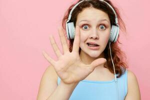 portrait of a young girl in headphones listening to music on a pink background unaltered photo