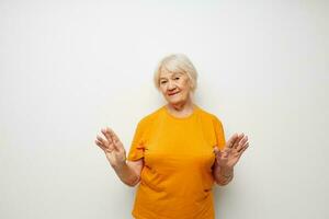 Photo of retired old lady in a yellow t-shirt posing light background