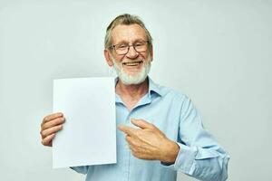 Senior grey-haired man in a blue shirt and glasses a white sheet of paper cropped view photo