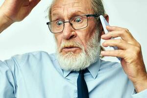 antiguo hombre con teléfono conmocionado en estudio en blanco antecedentes foto