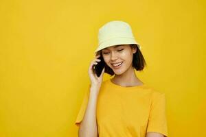 attractive woman yellow t-shirt and Hat summer style with phone isolated background photo