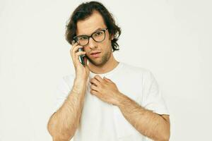 alegre hombre en un blanco camiseta comunicación por teléfono aislado antecedentes foto