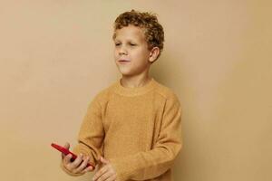Cheerful boy with red phone in hands posing beige background photo