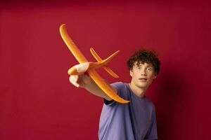 A young man with toy airplane entertainment red background unaltered photo
