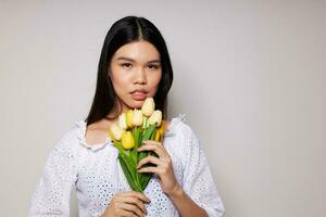 Charming young Asian woman romance bouquet of flowers near the face light background unaltered photo