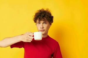 Young curly-haired man in a red T-shirt with a white cap in his hands isolated background unaltered photo