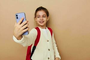 pretty young girl talking on the phone with a backpack beige background photo