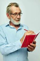 Portrait elderly man with red notebook and pen light background photo