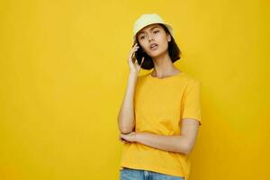 optimistic young woman yellow t-shirt and Hat summer style with phone Lifestyle unaltered photo