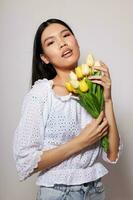 Charming young Asian woman romance bouquet of flowers near the face light background unaltered photo