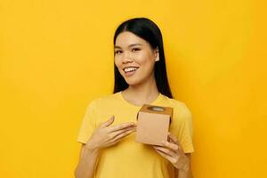 alegre mujer en un amarillo camiseta con un caja en su manos foto