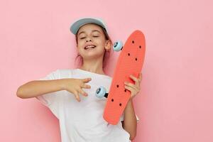 Portrait of happy smiling child girl cap in white t-shirt skateboard childhood unaltered photo