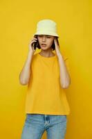 young beautiful woman yellow t-shirt and Hat summer style with phone Lifestyle unaltered photo