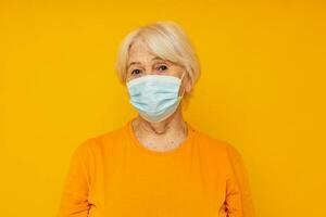 retrato de un antiguo simpático mujer en amarillo camisetas en médico mascaras de cerca emociones foto