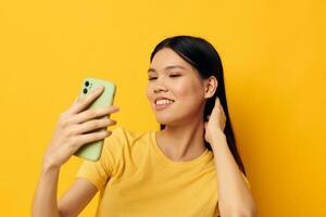 retrato asiático hermosa joven mujer con un teléfono en su manos hace un selfie aislado antecedentes inalterado foto