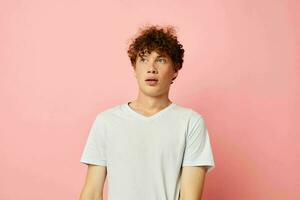 Young curly-haired man summer clothes white tshirt posing isolated background unaltered photo