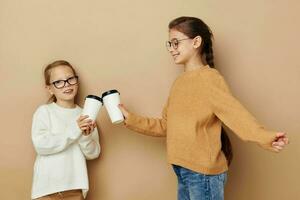 gracioso pequeño muchachas con lentes con un bebida foto