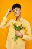 Photo of romantic young boyfriend with a fashionable hairstyle in yellow shirts with flowers yellow background unaltered