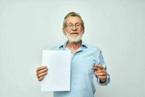 Portrait of happy senior man in a blue shirt and glasses a white sheet of paper cropped view photo