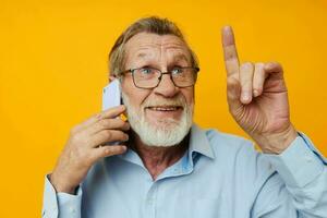 retrato de contento mayor hombre en un azul camisa y lentes hablando en el teléfono recortado ver foto