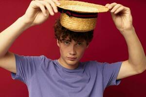 A young man in Hat purple t-shirts posing emotions red background unaltered photo