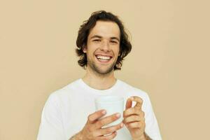 Cheerful man with a white mug in his hands emotions posing beige background photo