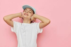 cute girl headphones in a white t-shirt and a cap pink background photo